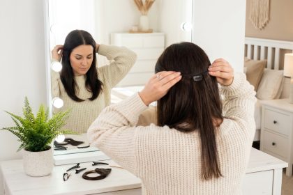 Femme appliquant des extensions à clips devant un miroir de coiffeuse dans une chambre moderne