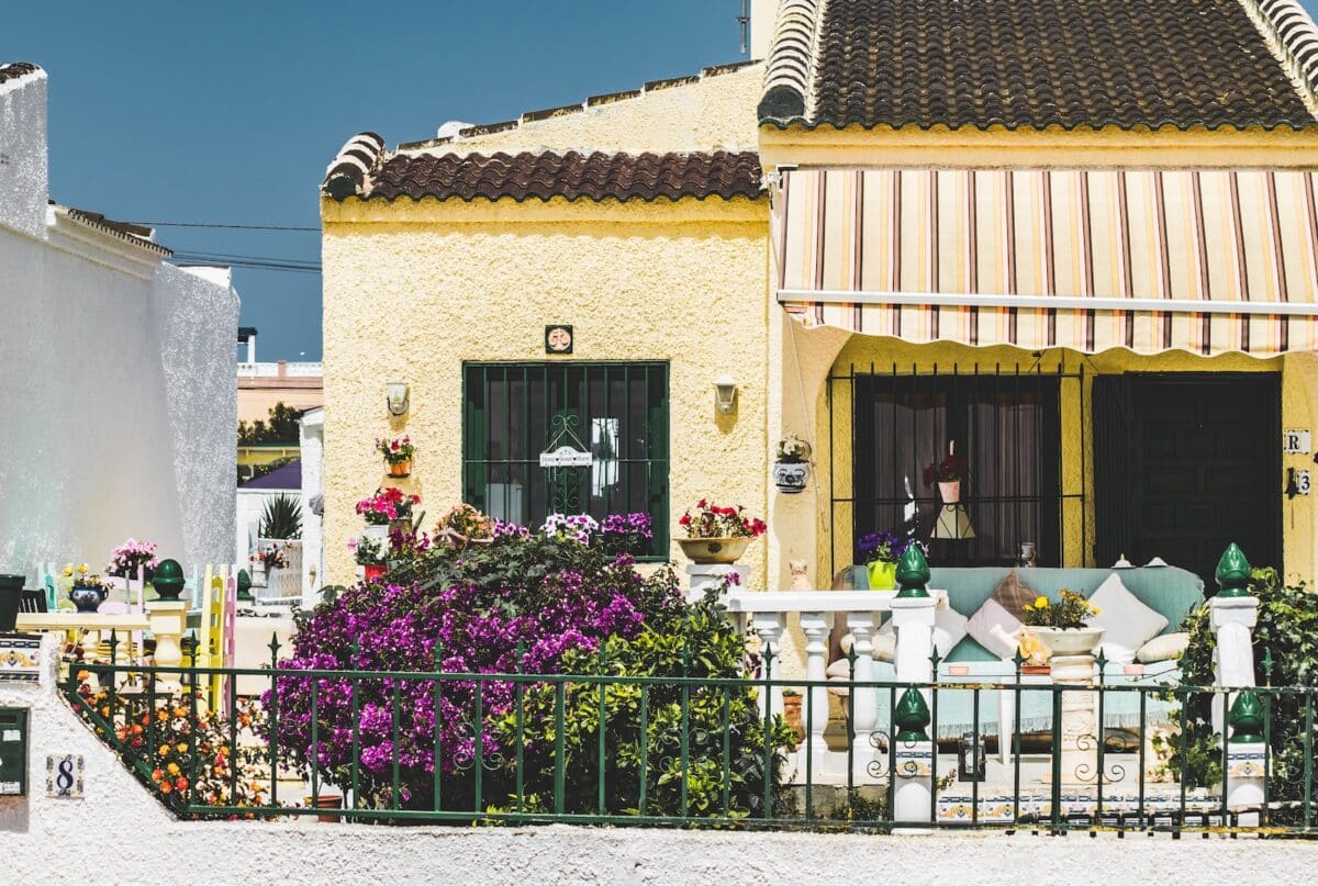 brown and white concrete house with purple flowers on the window